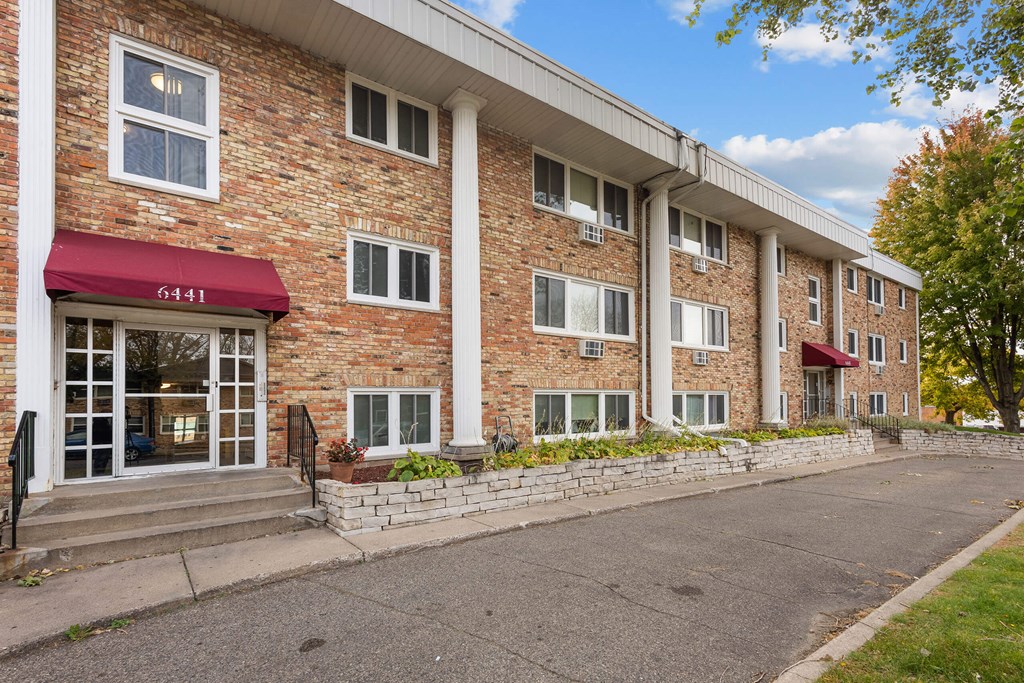 a brick building with a red awning and a sidewalk in front of it