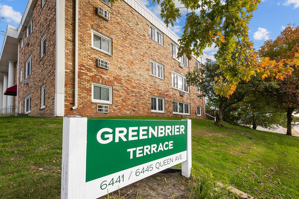 A sign for Greenbrier Terrace stands in front of a brick building.