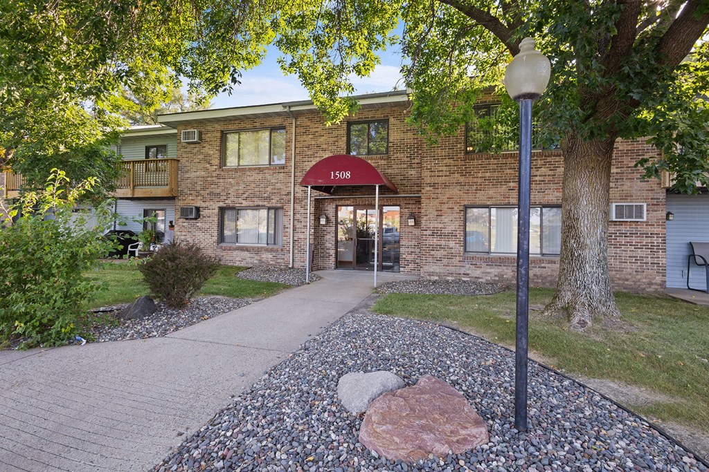 A building with the number 1508 on it is surrounded by trees and has a red awning.