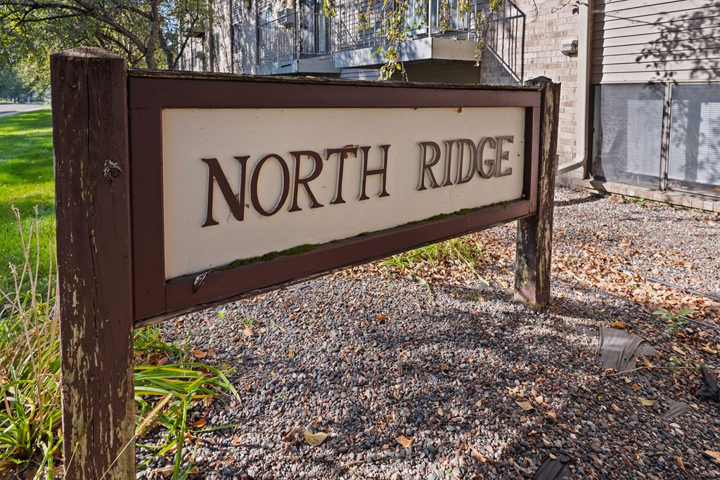 A brown sign that says North Ridge stands in front of a building.