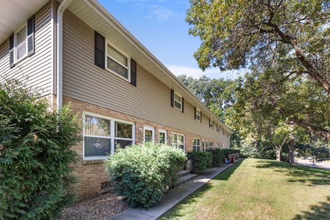 A building with a brown siding and a green lawn in front.