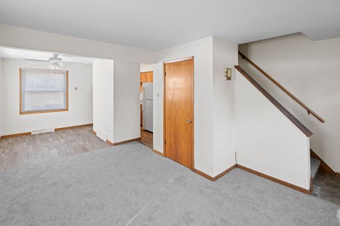A room with a grey carpet and a wooden door.