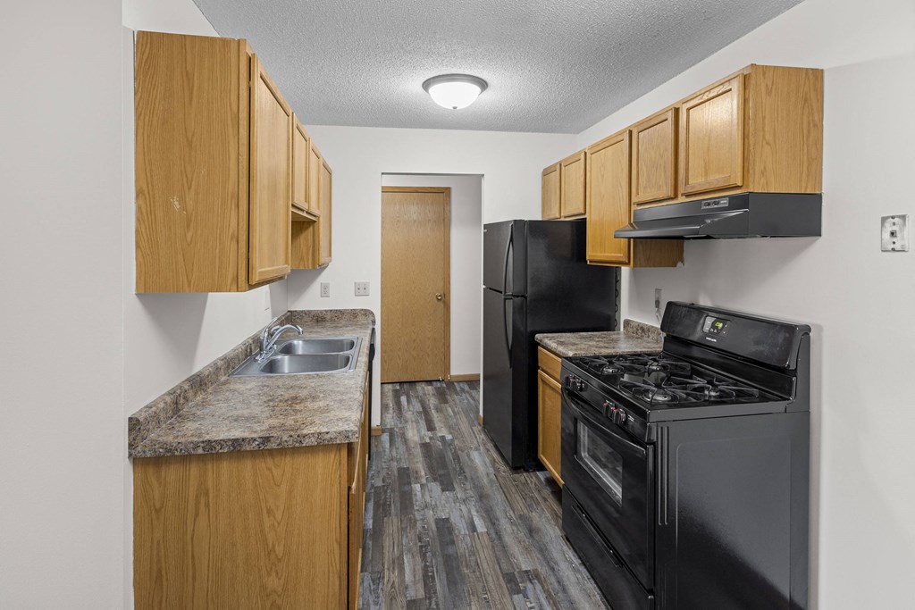 our apartments have a kitchen with black appliances and wooden cabinets