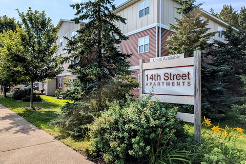 A sign for 14th Street Apartments is in front of a building.