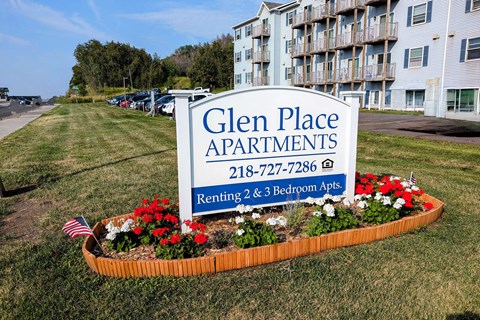 a sign for glen place apartments in front of a garden of flowers