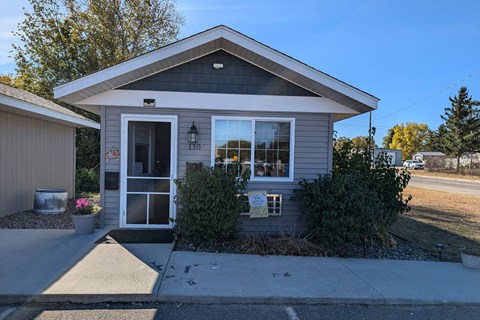 a small gray house with a sidewalk in front of it