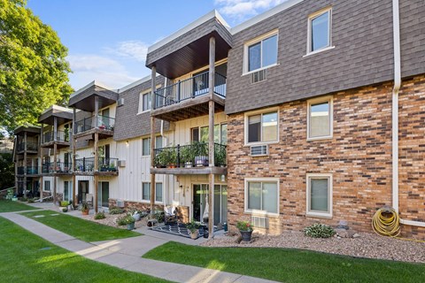 A row of multi-story apartment buildings with balconies and potted plants.