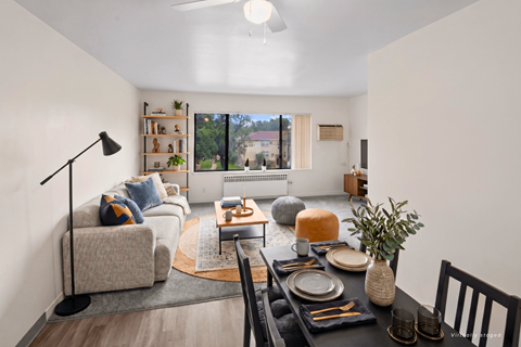A well-lit living room with a dining table set for two.