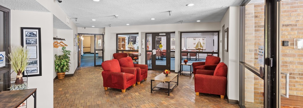 A living room with red chairs and a wooden floor.