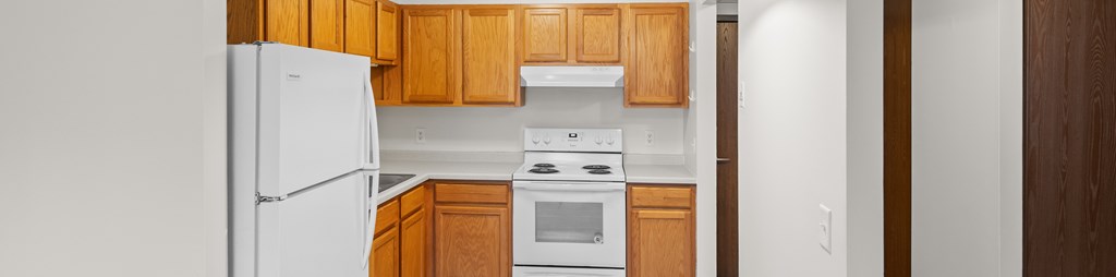 A white refrigerator is in a kitchen with wooden cabinets.
