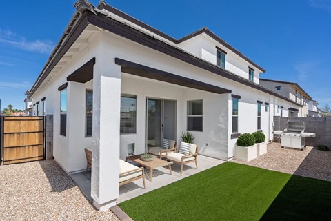 A modern house with a white exterior and a patio area with a table and chairs.