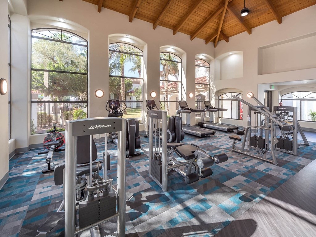 a gym with weights and cardio equipment in a building with tall windows