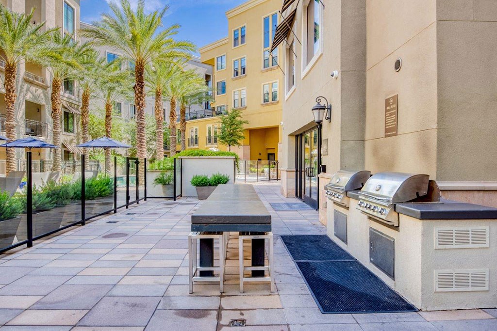 a patio with a grill and a table in front of a building