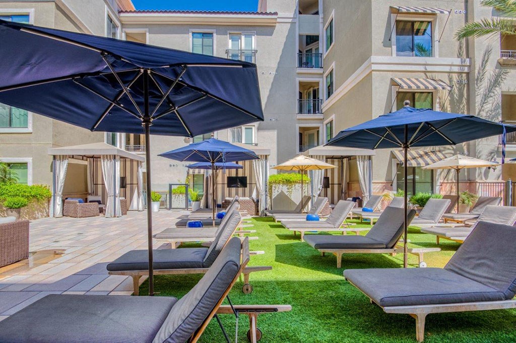 a patio with lounge chairs and umbrellas at a hotel