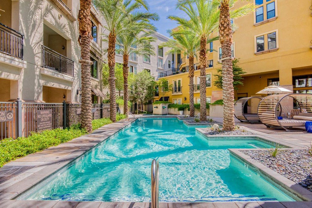 a swimming pool with palm trees in front of a building