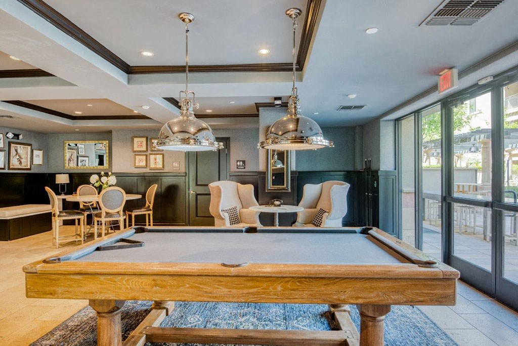 a pool table in the center of a living room with a bar and chairs