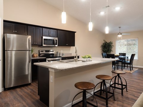 a kitchen with a large island and a stainless steel refrigerator