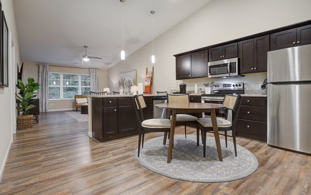 an open kitchen and dining room with stainless steel appliances and a table and chairs