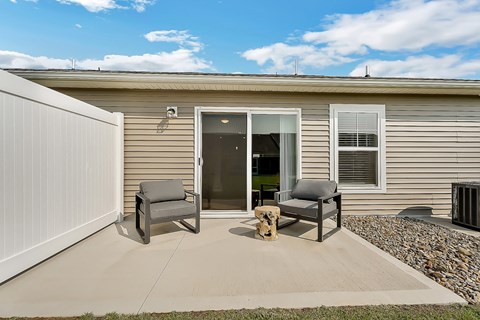a patio with two chairs in front of a house
