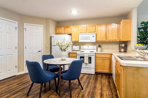 a kitchen with white appliances and a table with chairs