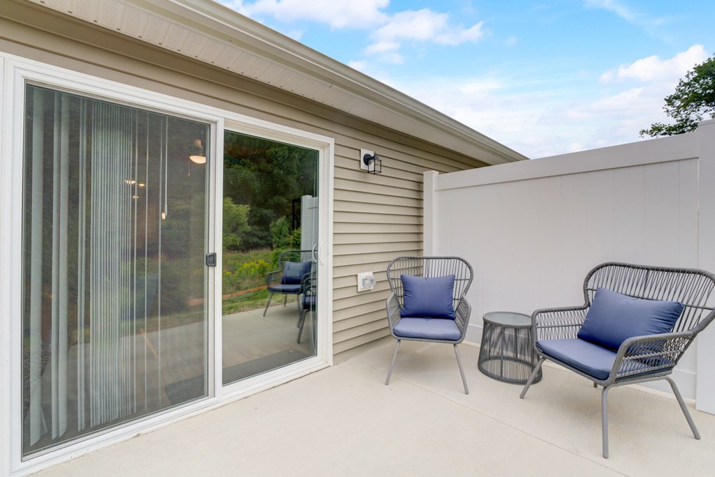 a patio with two chairs and a table and a sliding glass door