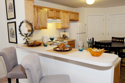a kitchen and dining area with a counter and chairs and a dining table with food