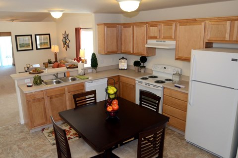 a kitchen with white appliances and wooden cabinets and a dining table