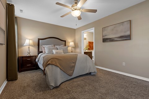 A bedroom with a bed, two lamps, and a ceiling fan.