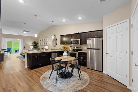 A modern kitchen with a dining table and chairs in the middle.