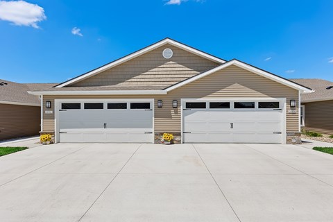 A two-car garage with a tan house in the background.
