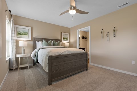 A bedroom with a large bed and a ceiling fan.