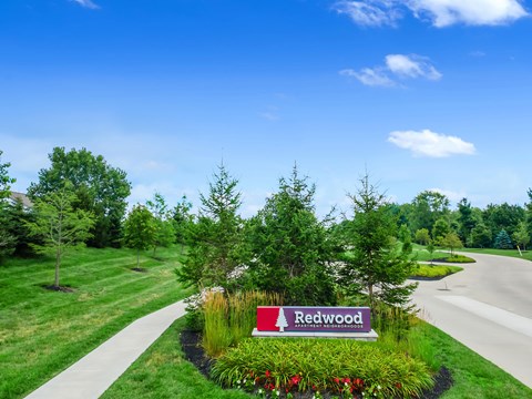 A sign that says Redwood in front of a grassy area.