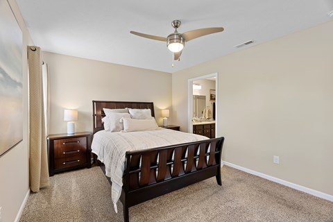 A bedroom with a large bed and a ceiling fan.