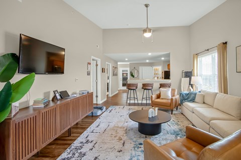 A living room with a large couch, a coffee table, and a television mounted on the wall.