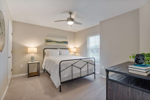 A bedroom with a bed, nightstands, and a ceiling fan.