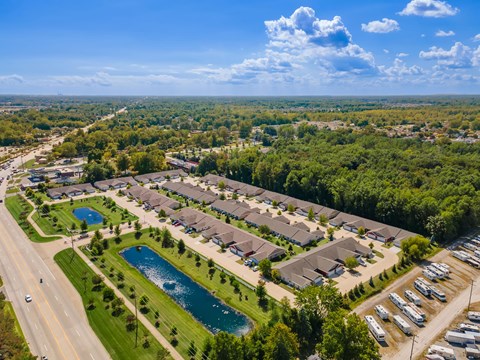 A bird's eye view of a residential area with houses, a swimming pool, and a parking lot.