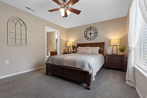 A bedroom with a bed, nightstands, and a ceiling fan.