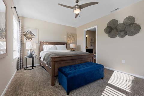 A bedroom with a bed, a bench, and a ceiling fan.