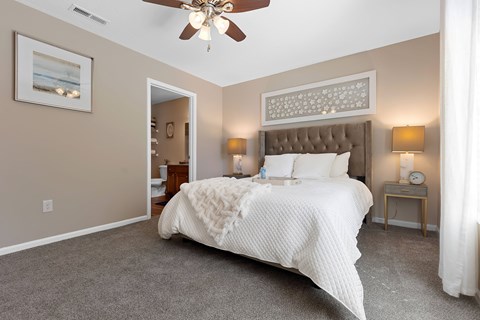 A bedroom with a large bed and a ceiling fan.
