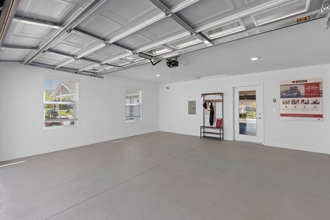 A spacious room with a white ceiling and walls, a window with blinds, and a few posters on the wall.