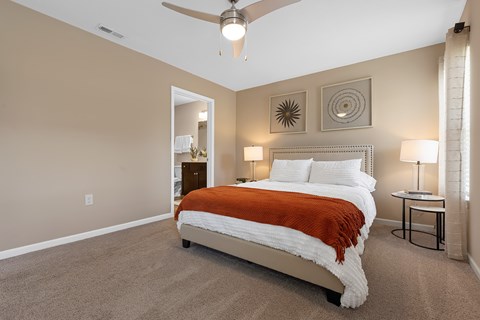 A bedroom with a bed, two lamps, and a ceiling fan.