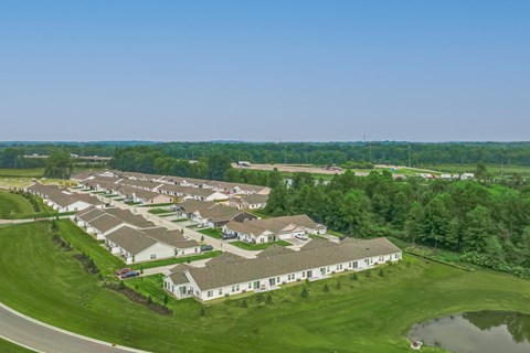 A bird's eye view of a residential area with houses and a pond.