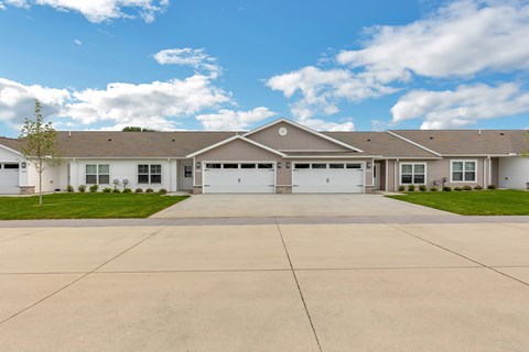 A large, two-story house with a garage and a driveway in front.