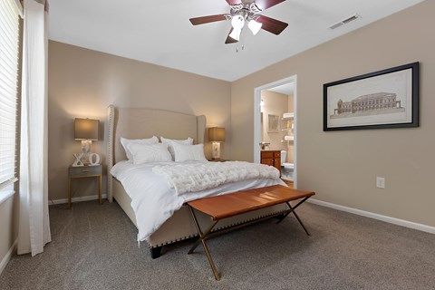 A bedroom with a bed, a bench, and a painting on the wall.