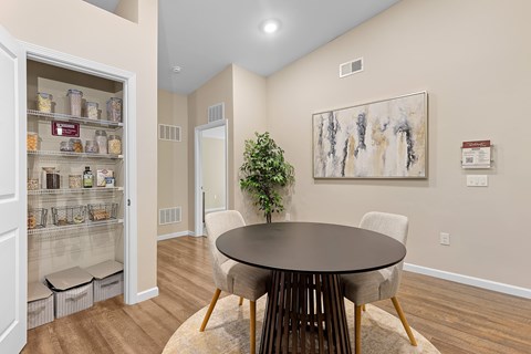 A dining room with a table and chairs and a potted plant.