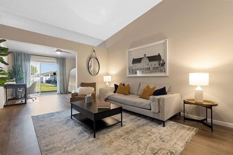 A living room with a white couch, a coffee table, and a painting on the wall.