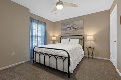 A bedroom with a bed, two lamps, and a painting on the wall.