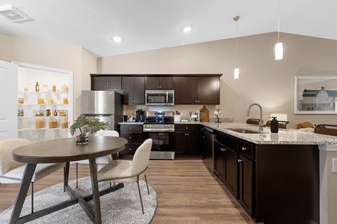A modern kitchen with dark brown cabinets and a round table with two chairs.