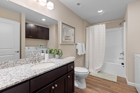 A bathroom with a marble countertop and dark brown cabinets.
