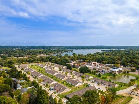 A bird's eye view of a residential area with houses, trees, and a body of water.